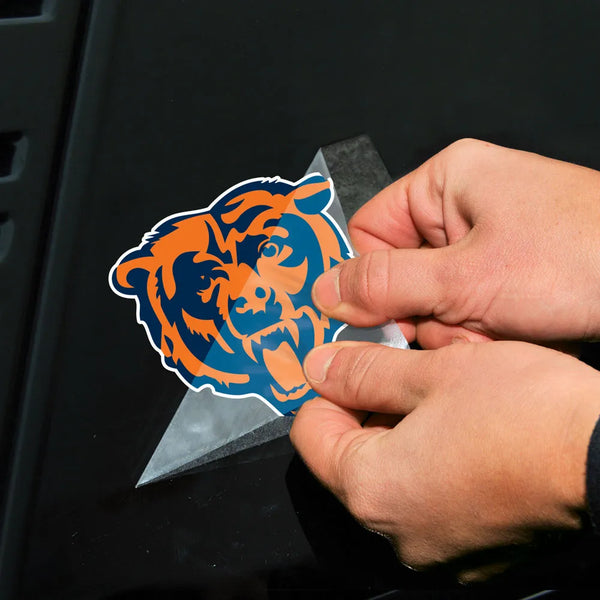 Person applying a blue and orange bear logo decal to a black surface